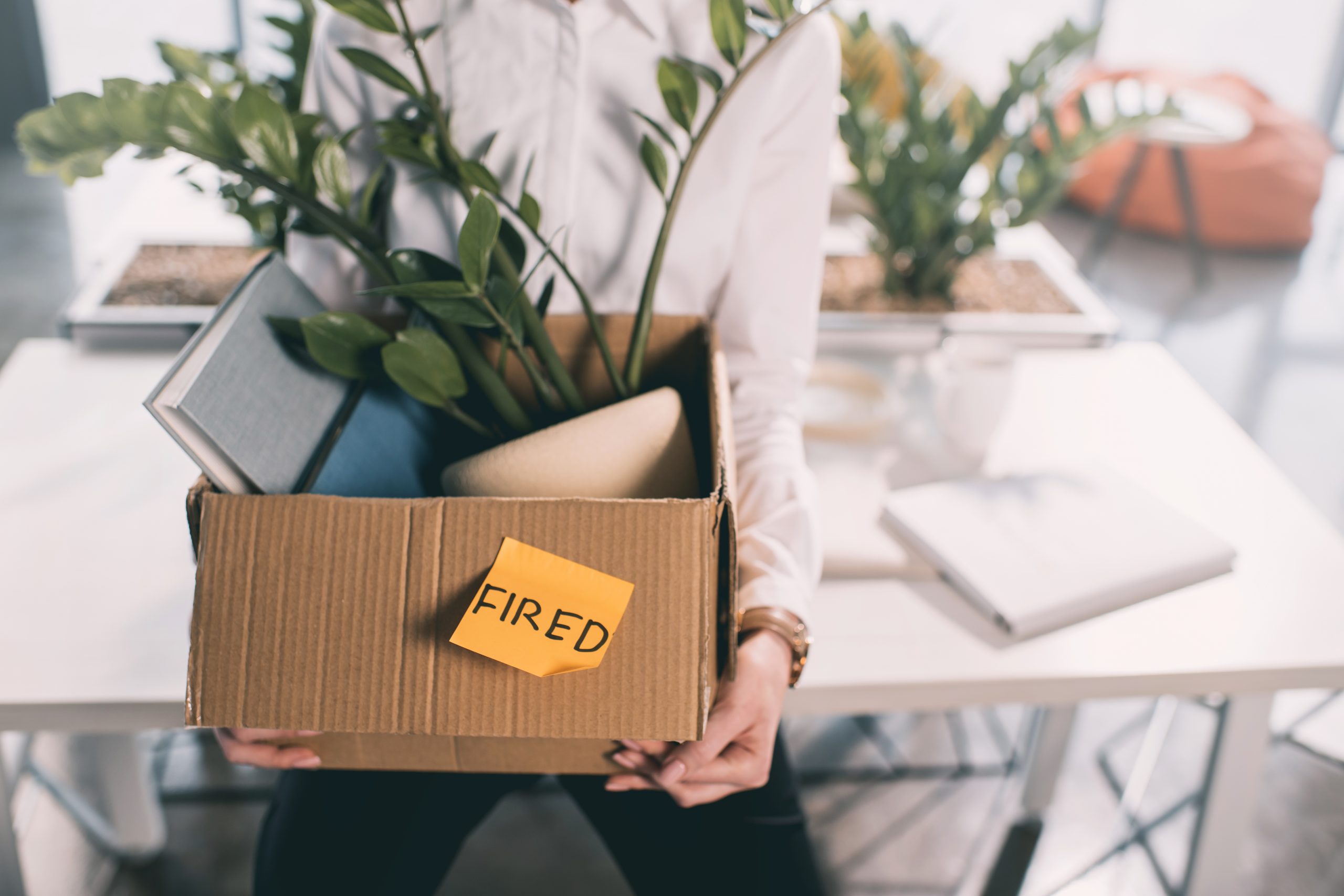 person holding a box with item and a sticky note that says "fired" on the box